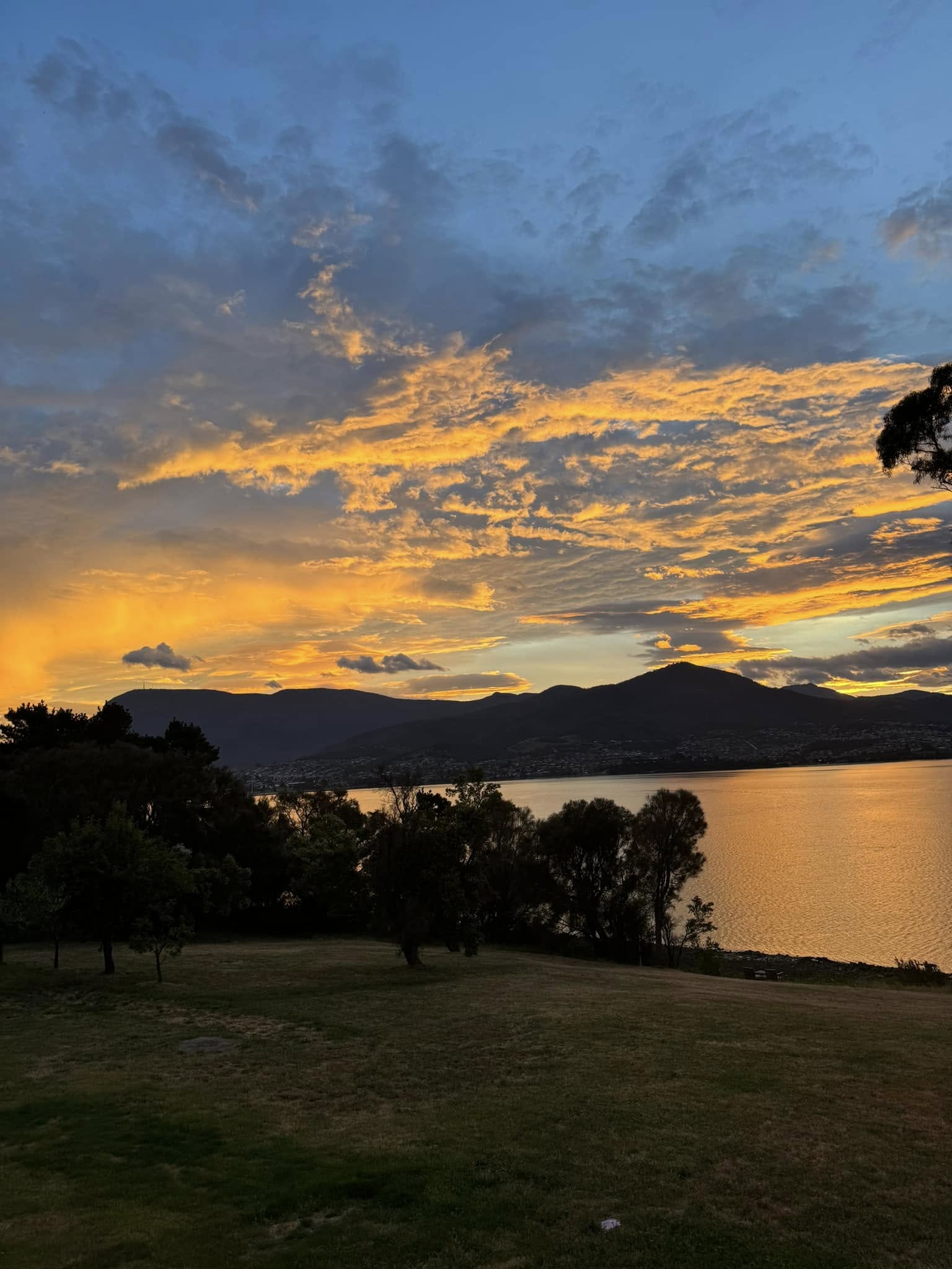 Golden evening sky over the River Derwent and waterfront grounds at Otago Cottage
